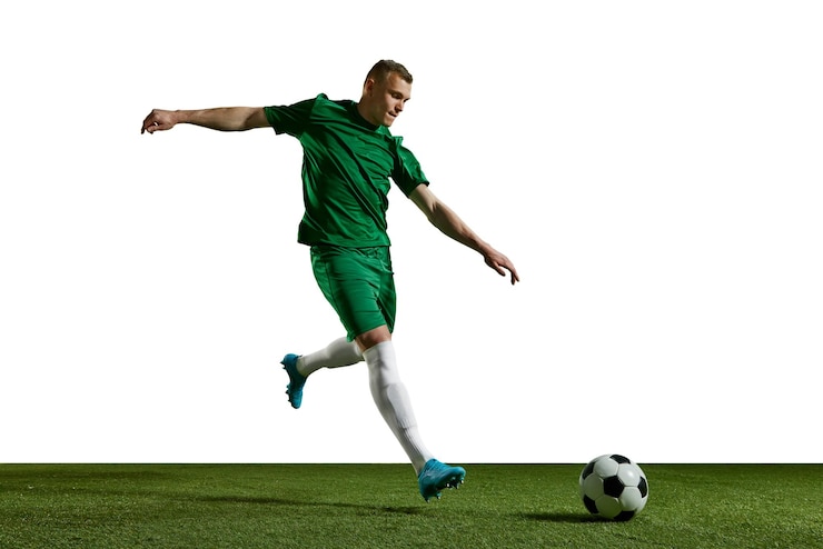 Photo un jeune homme en uniforme vert joue au football en mouvement sur un terrain de sport contre des blancs.
