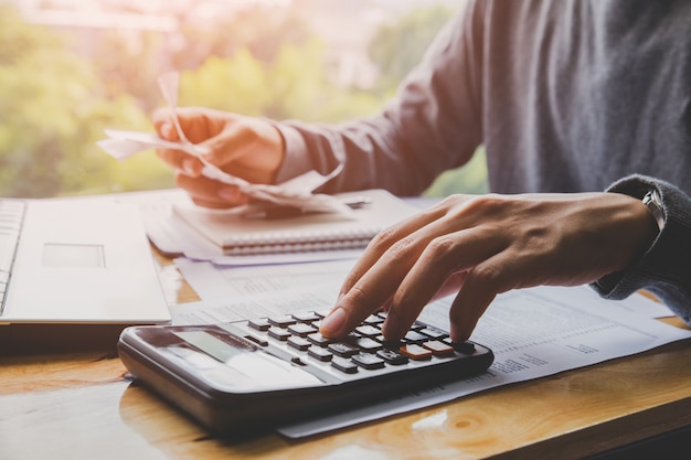 Jeune homme en utilisant la calculatrice et calculer les factures dans le bureau à domicile.