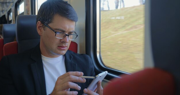 Jeune homme utilisant une cellule pour naviguer en ligne dans le train