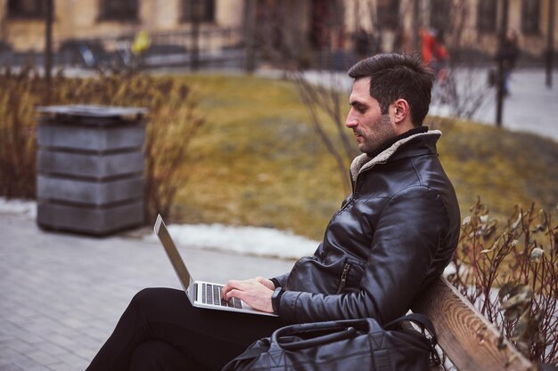 Jeune homme utilisant un ordinateur portable dans une rue urbaine