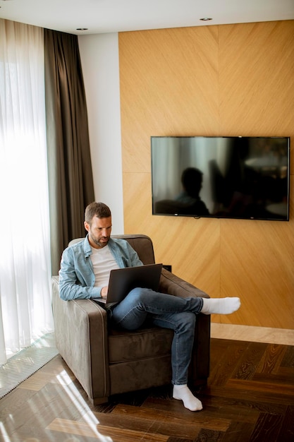 Jeune homme utilisant un ordinateur portable dans le salon