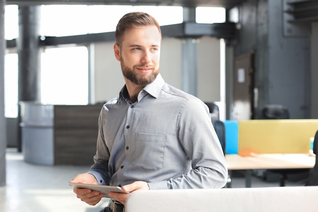 Jeune homme utilisant sa tablette au bureau.