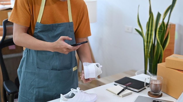 Jeune homme utilisant un smartphone prenant une photo du produit à télécharger sur le site Web