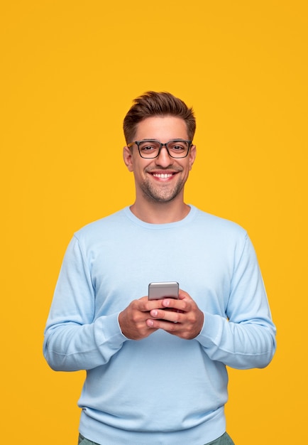 Jeune homme utilisant un smartphone et souriant
