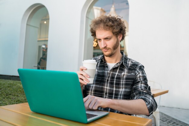 Jeune homme utilisant son ordinateur portable dans un café.