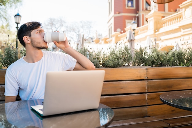 Jeune homme utilisant son ordinateur portable dans un café.