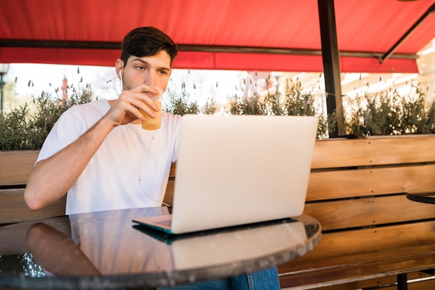 Jeune homme utilisant son ordinateur portable dans un café.