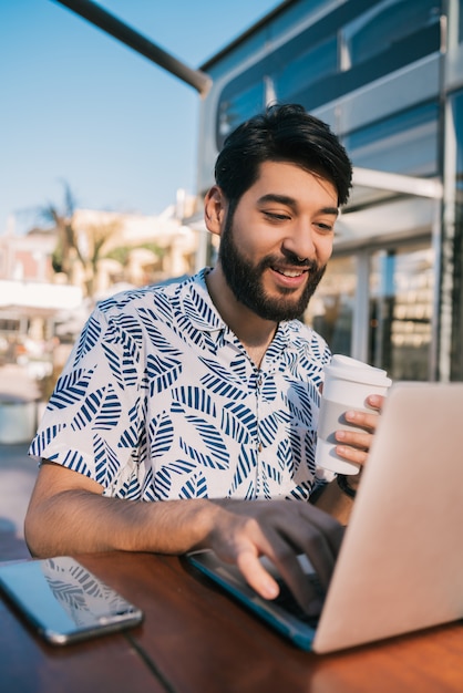 Jeune homme utilisant son ordinateur portable dans un café