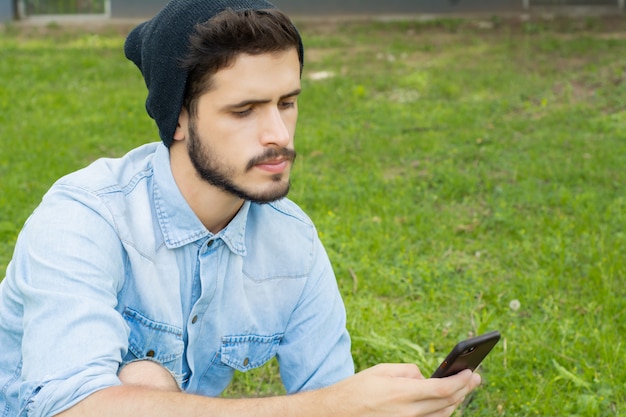 Jeune homme utilisant son téléphone. En plein air.