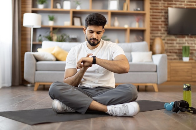 Photo jeune homme utilisant un tracker de fitness pour l'entraînement à domicile