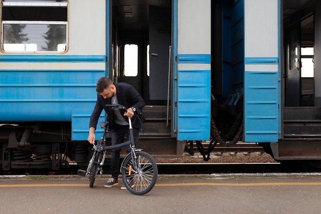 Photo jeune homme utilisant un vélo pliant lors d'un voyage en train