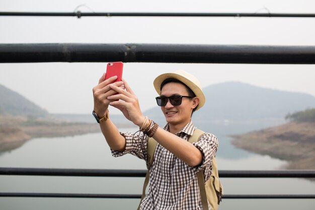 Jeune homme, utilisation, téléphone, et, selfie, sur, pont