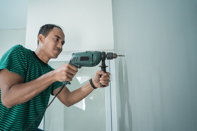 jeune homme a utilisé une perceuse sur le mur