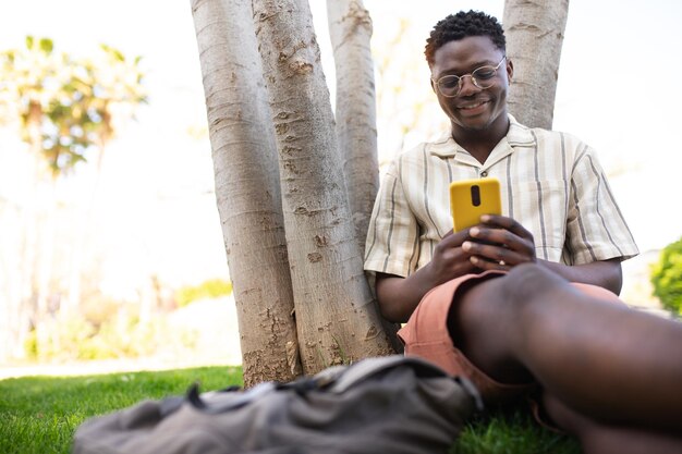 Un jeune homme utilise son téléphone à l'extérieur. Un étudiant afro-américain sur le campus envoie un texto.