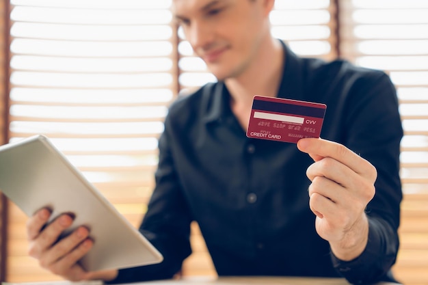 Un jeune homme utilise une tablette avec une carte de crédit pour les services bancaires sur Internet.