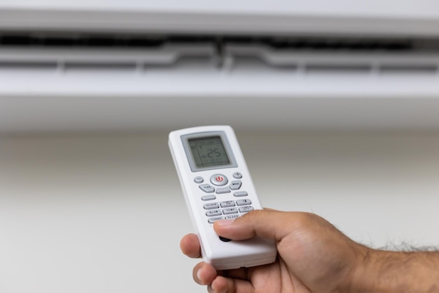 Le jeune homme a utilisé la télécommande pour allumer la climatisation. Réglez la température pour refroidir. Dans le salon à la maison