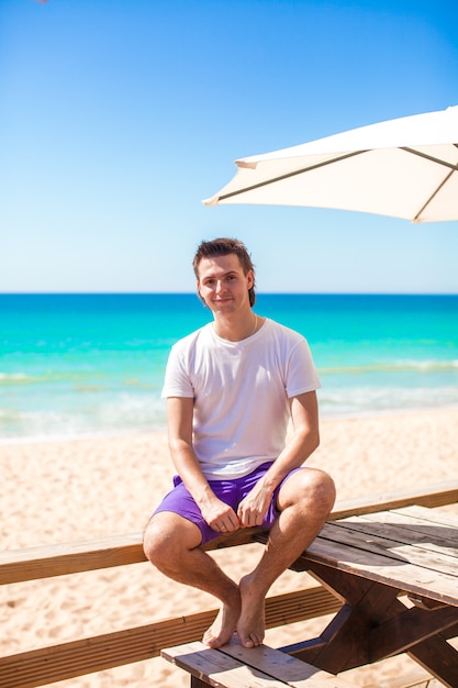 Jeune homme en vacances de plage tropicale au café en plein air