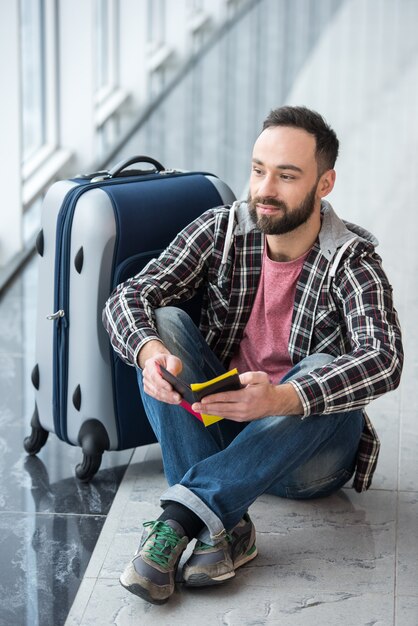 Jeune homme avec une valise et un passeport prêt à voyager.