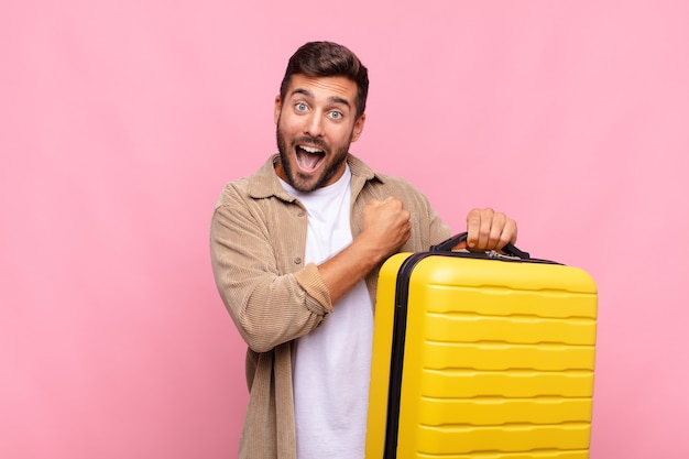 Jeune homme avec valise se sentant heureux, c'est le temps du voyage!