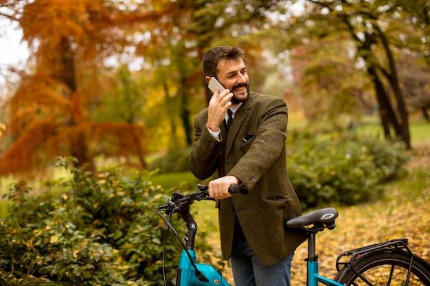 Jeune homme avec vélo électrique dans le parc en automne