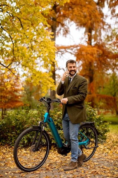 Jeune homme avec vélo électrique dans le parc en automne