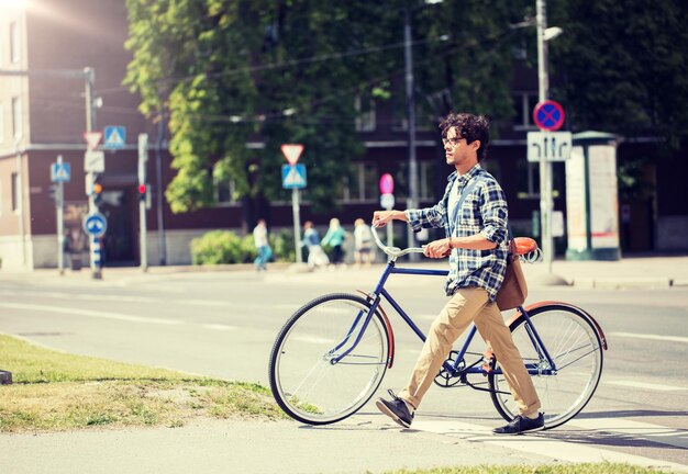 jeune homme avec vélo à engrenage fixe sur le trottoir