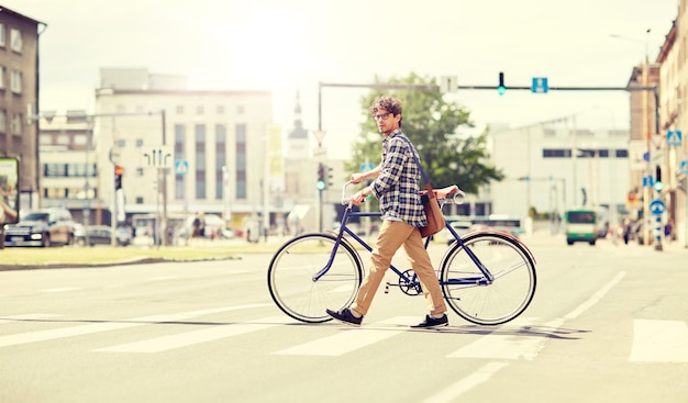 Photo jeune homme avec vélo à engrenage fixe sur le trottoir