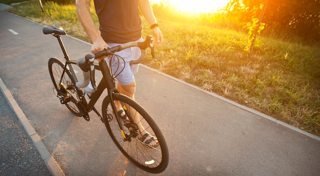 Le jeune homme à vélo marche sur la route