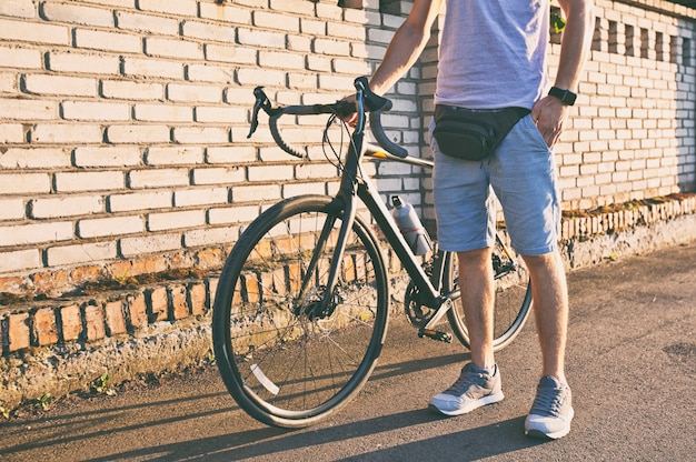 Le jeune homme à vélo marche sur la route