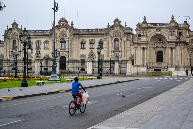 Un jeune homme à vélo avec un sac plein de pain est en route pour un palais