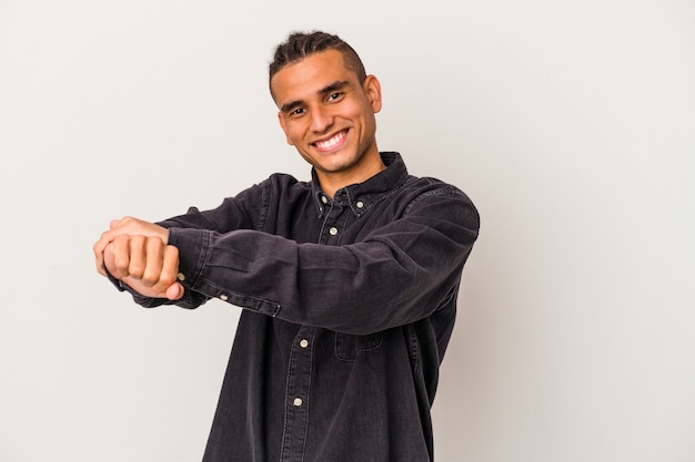 Jeune homme vénézuélien isolé sur fond blanc étirant les bras, position détendue.