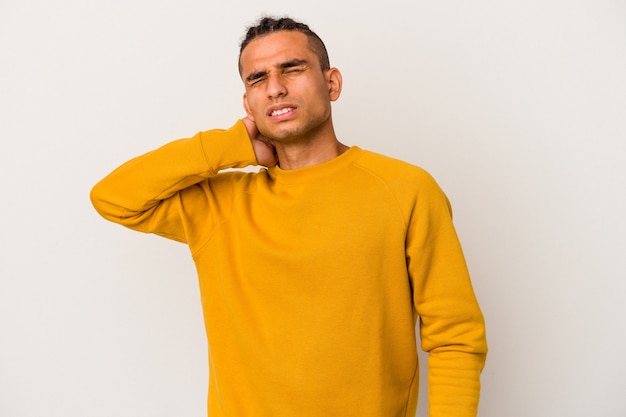 Jeune homme vénézuélien isolé sur un mur blanc ayant une douleur au cou due au stress, en le massant et en le touchant avec la main.