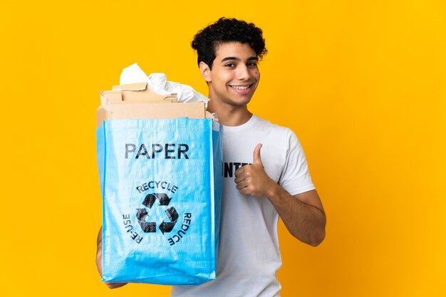 Jeune homme vénézuélien tenant un sac de recyclage plein de papier à recycler en donnant un geste de pouce en l'air