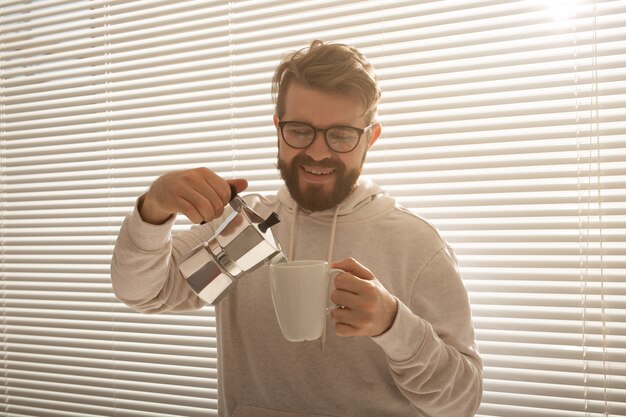 Jeune homme versant du café du pot de moka au matin. Concept de petit-déjeuner et de pause.