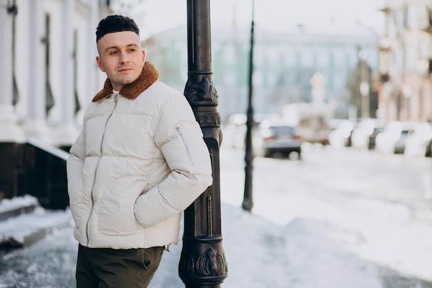 Jeune homme en veste d'hiver blanche à l'extérieur de la rue