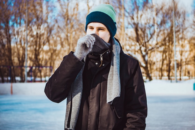 Jeune homme en vêtements chauds et écharpe un jour d'hiver