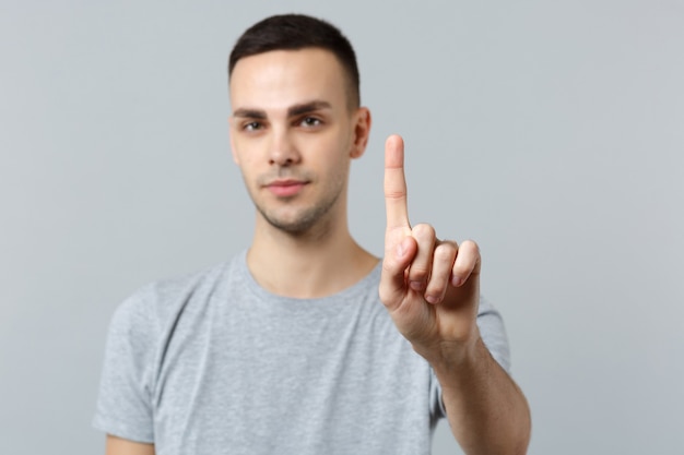 Un jeune homme en vêtements décontractés touche quelque chose comme un clic sur le bouton, pointant vers un écran virtuel flottant