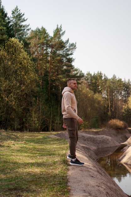 Un jeune homme vêtu d'un costume confortable se promène dans la forêt au bord de la rivière. Concept de randonnée et de loisirs de plein air