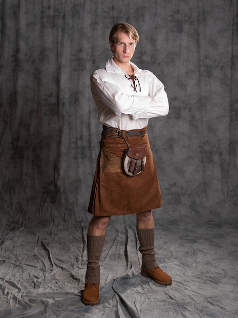 Un jeune homme vêtu d'un kilt en cuir et d'un chemisier blanc à lacets un chevalier écossais