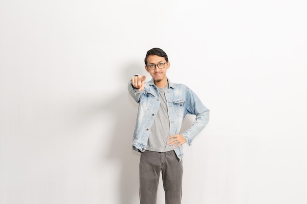 Photo un jeune homme vêtu d'une veste en jean pointe vers la caméra et pointe vers la caméra.