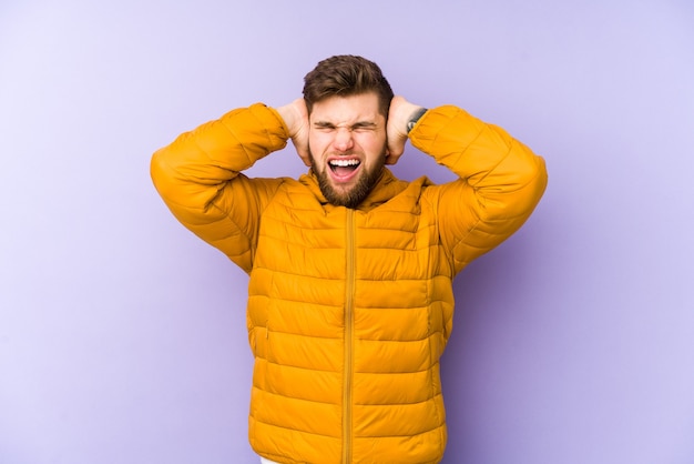 Jeune homme violet couvrant les oreilles avec les mains en essayant de ne pas entendre un son trop fort.