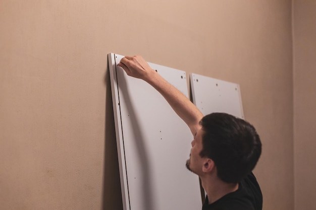 Un jeune homme visse une vis dans une planche avec ses mains