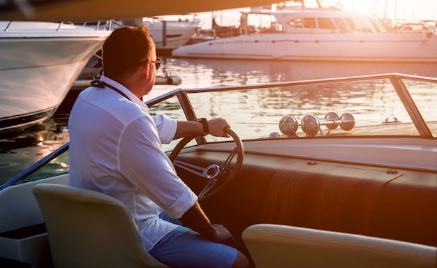 Jeune homme sur voilier. Les mains tiennent le volant