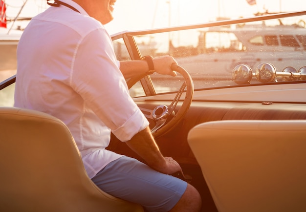 Jeune homme sur voilier. Les mains tiennent le volant