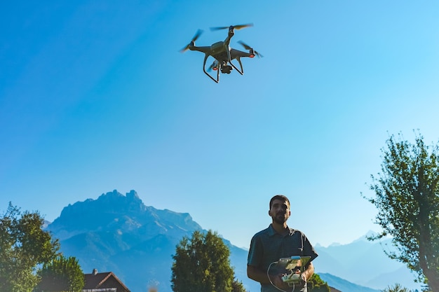 Un jeune homme volant un drone sur un paysage montagneux incroyable Un homme opérant un drone avec télécommande prenant des photos et des vidéos aériennes