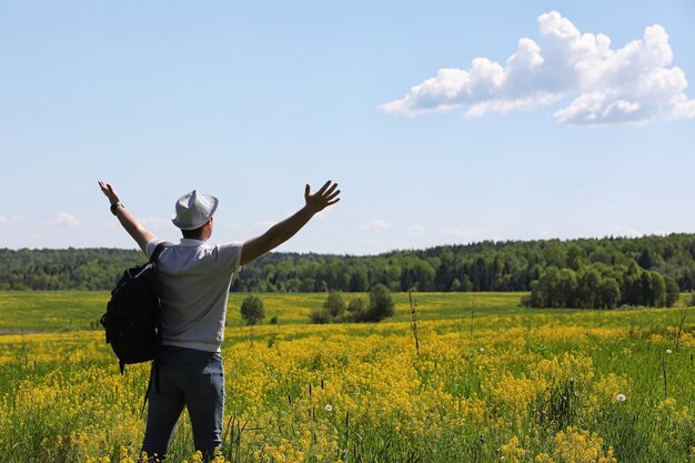 Le jeune homme voyage avec un sac à dos un jour d'été dehors