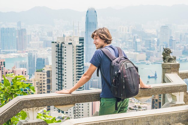 Jeune homme voyageur au sommet de Victoria dans le contexte de Hong Kong.