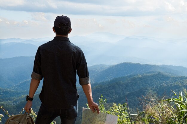 Jeune homme voyageur avec carte sac à dos relaxant en plein air avec des montagnes Rocheuses sur fond Vacances d&#39;été et concept de randonnée Lifestyle