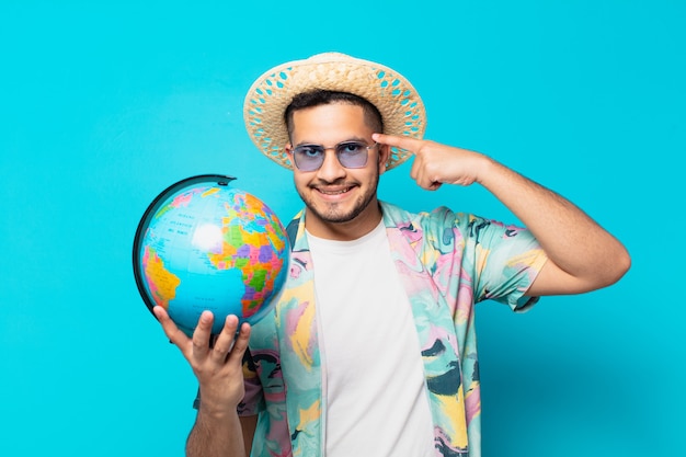 Jeune homme voyageur hispanique expression de pensée et tenant un globe terrestre