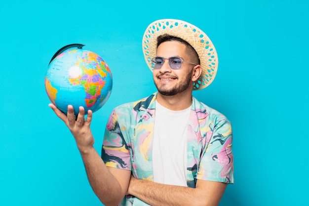 Jeune homme voyageur hispanique pensant à l'expression et tenant un globe terrestre